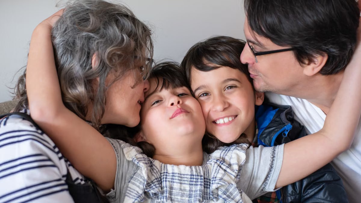 A joyful family of four sharing a warm embrace, highlighting love and togetherness indoors.